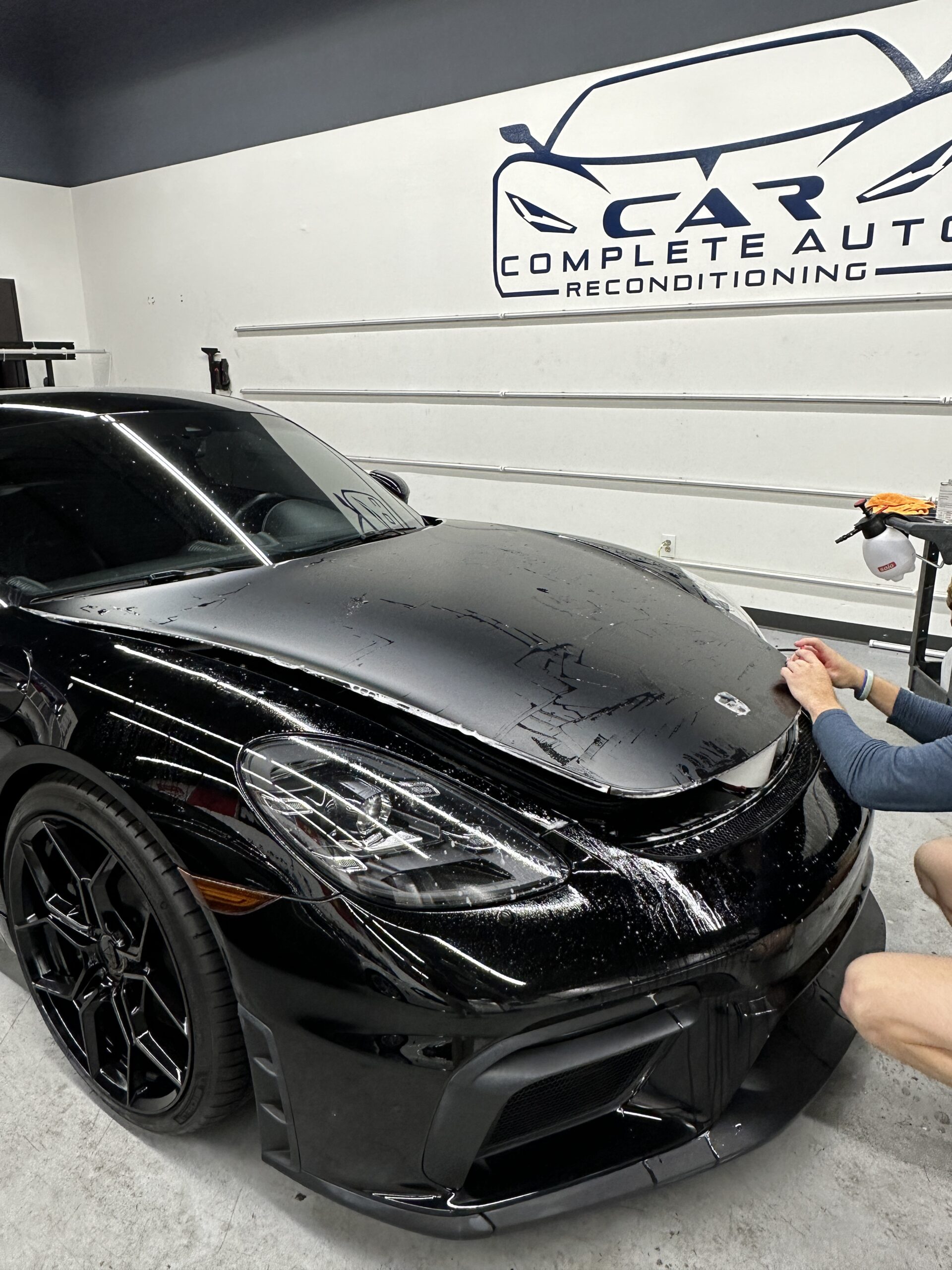 XPEL paint protection film installation on a black sports car at Car and Air
